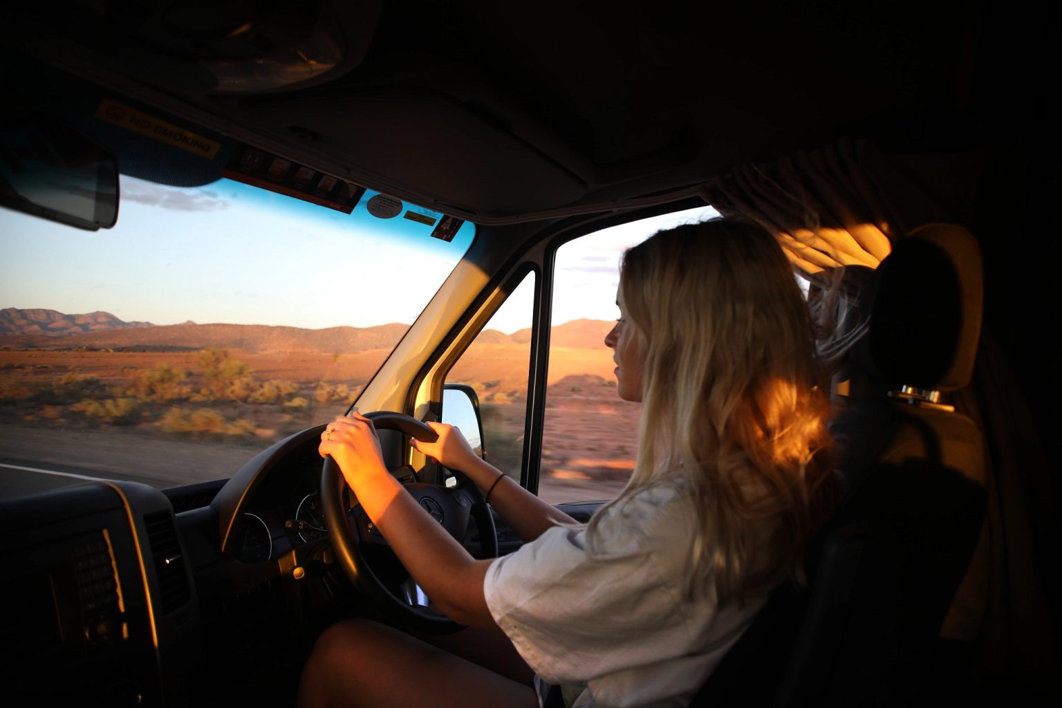 Woman driving a campervan at sunset, Flinders Ranges, South Australia