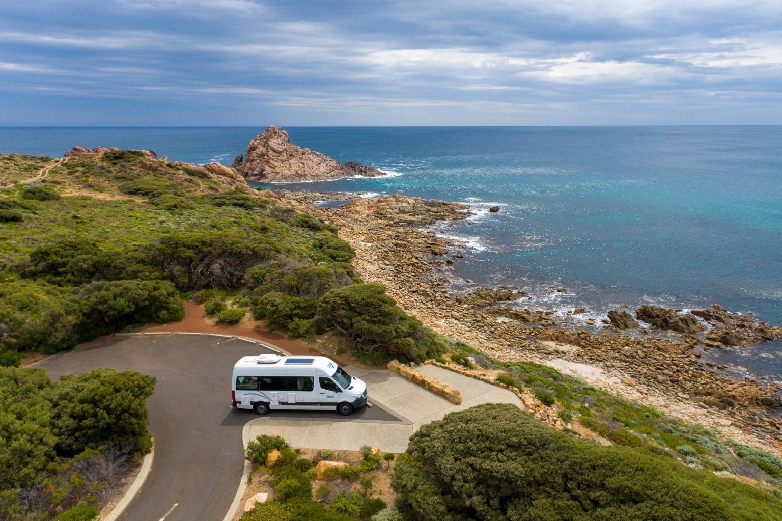 Campervan on a winding road above a rocky coastline, Margaret River, Western Australia