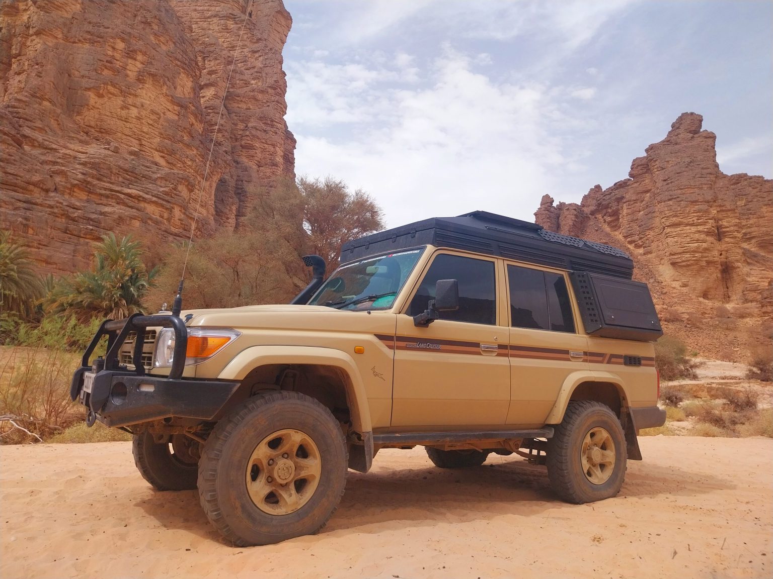 Land Cruiser parked among red sandstone canyon walls in the Algerian Sahara