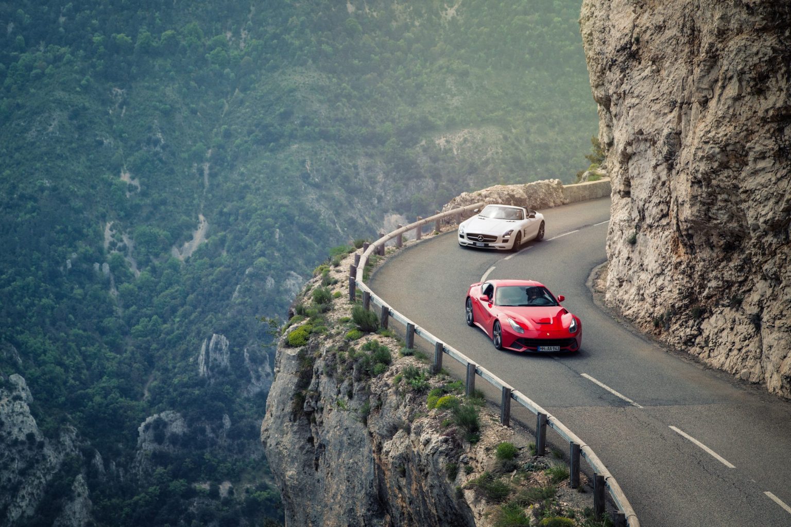 Two supercars on a cliff road above the French Riviera