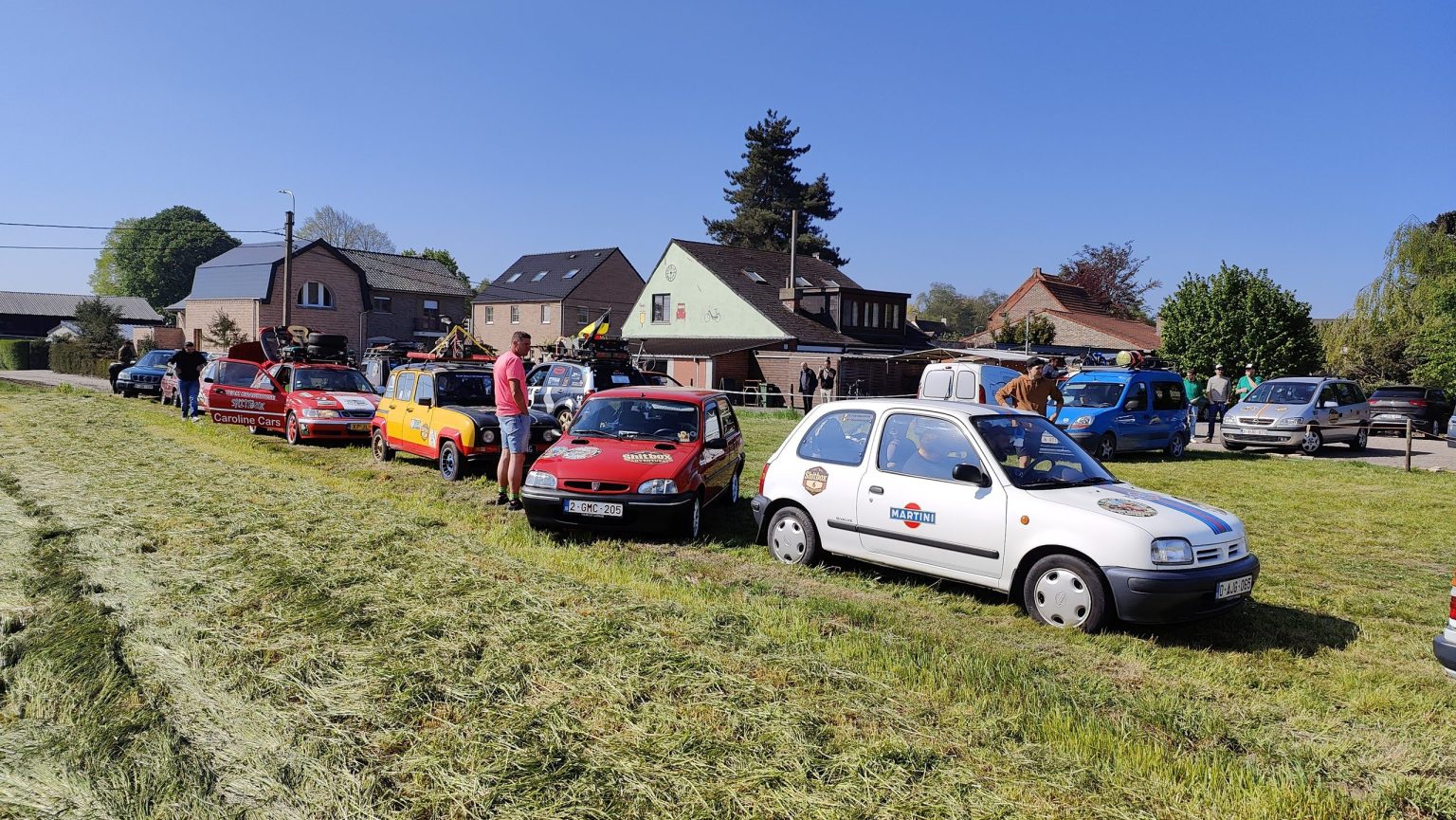 Rally cars gathered on a village green before the start