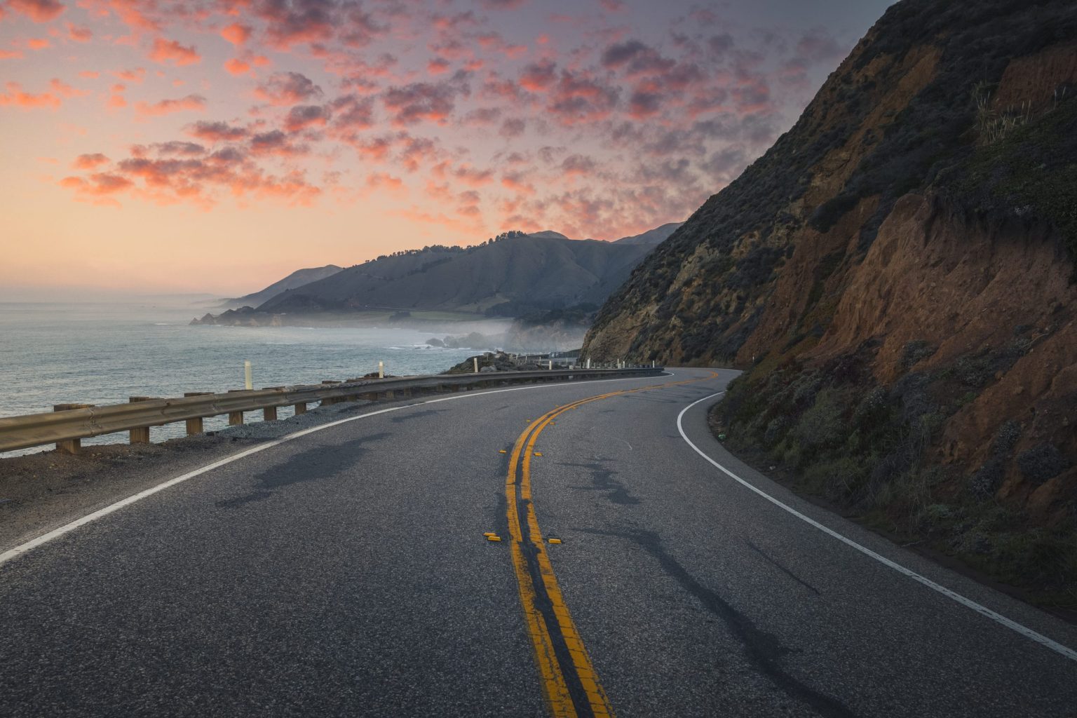 Highway 1 winding along the Big Sur coast at sunset