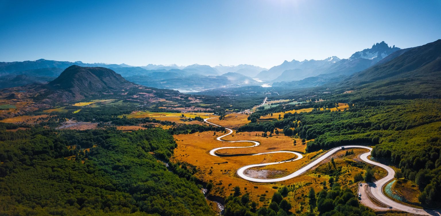 Road winding through a green valley below the Andes on the Carretera Austral, Chile