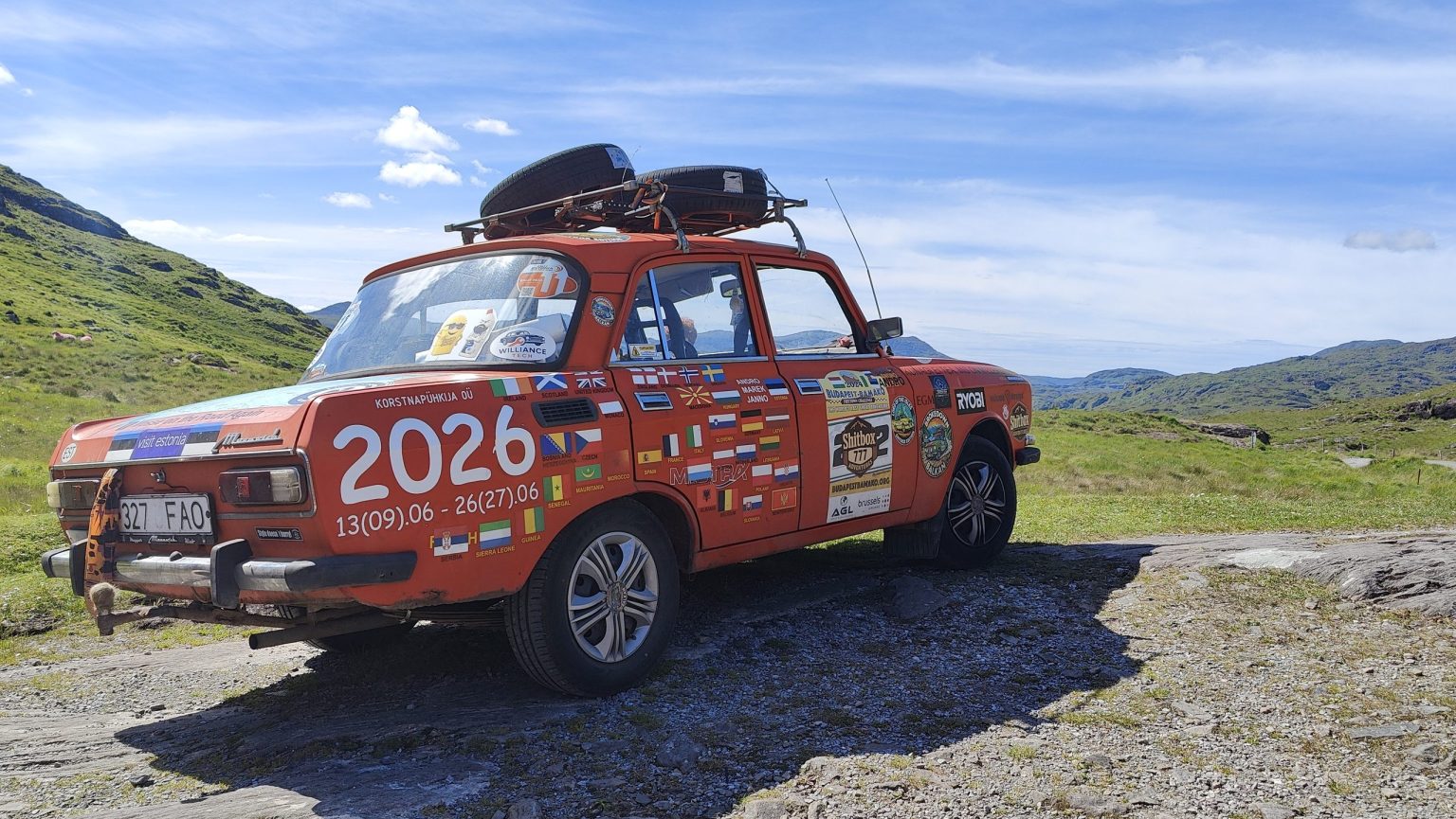 Sticker-covered rally car on a high mountain gravel plateau