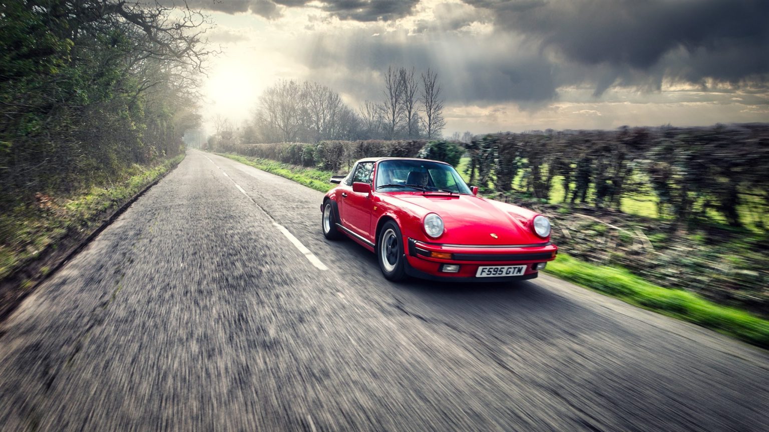 Red classic Porsche 911 on a country lane in the Cotswolds