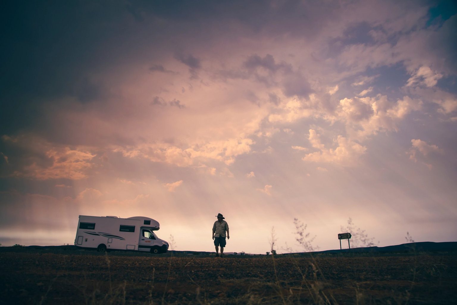 Silhouette of a person beside a motorhome under a sunset sky, Alice Springs, the Northern Territory