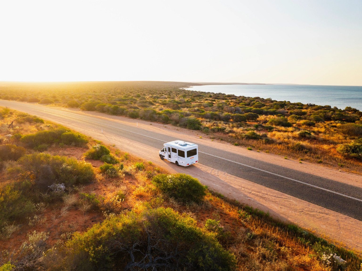 Campervan on a coastal road through golden scrubland, Monkey Mia, Western Australia