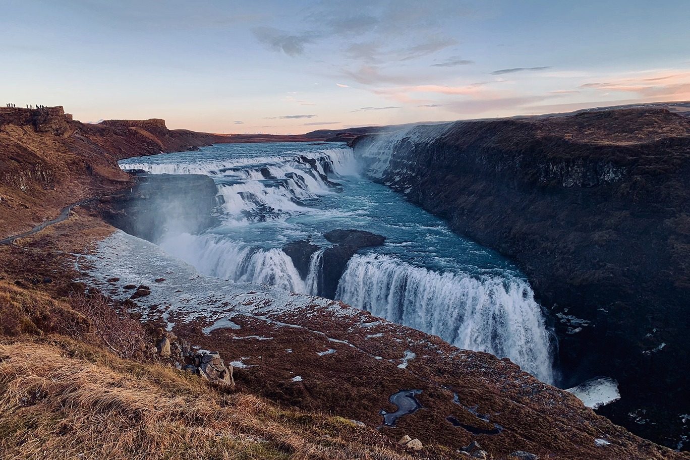 Wide waterfall dropping into a rocky canyon at dusk in Iceland