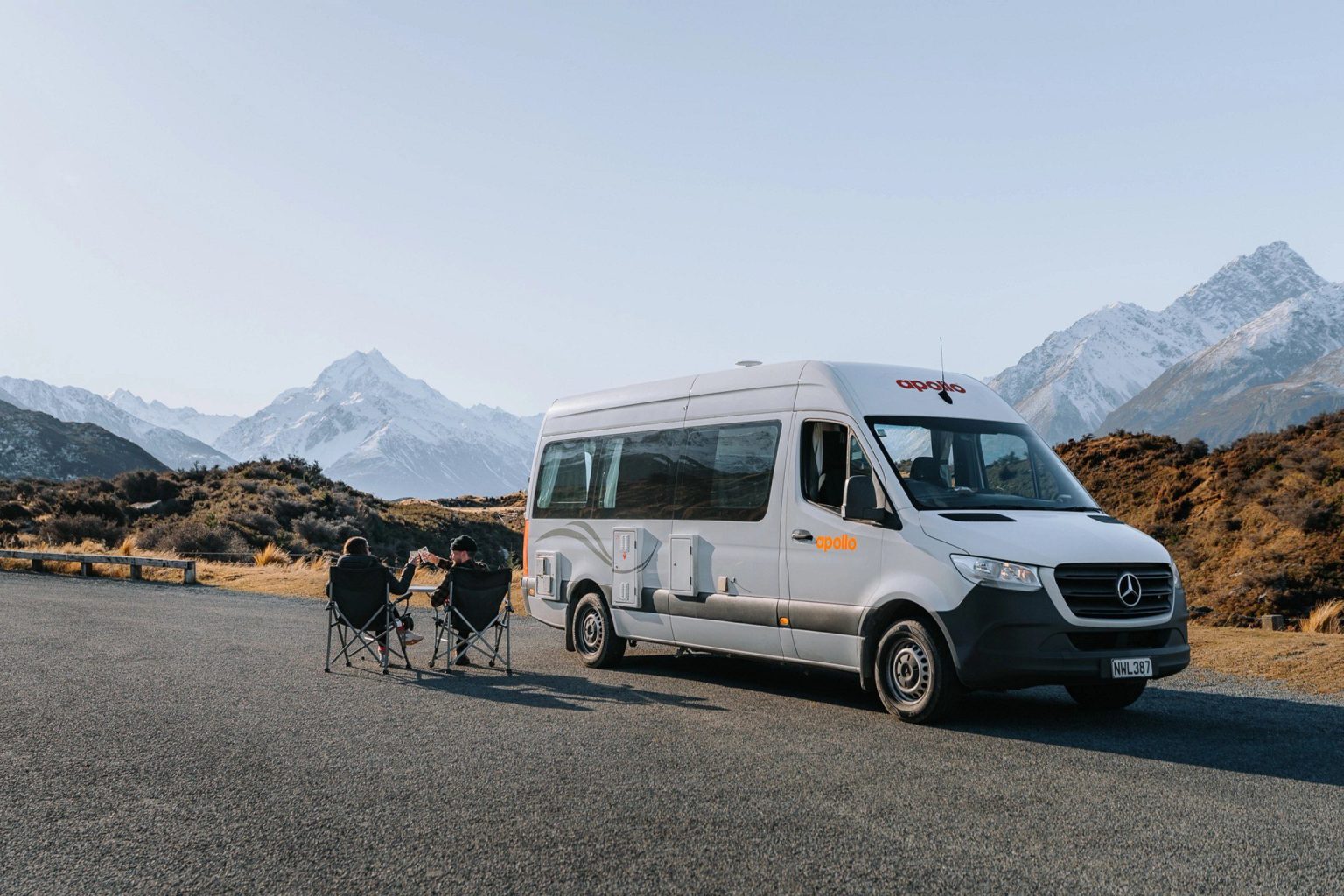 Couple with bikes beside a campervan below snowy mountains, Mount Cook, New Zealand's South Island