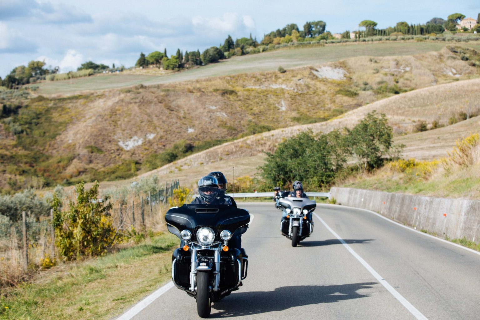 Two riders on Harley-Davidson touring bikes on a country road in southern Italy