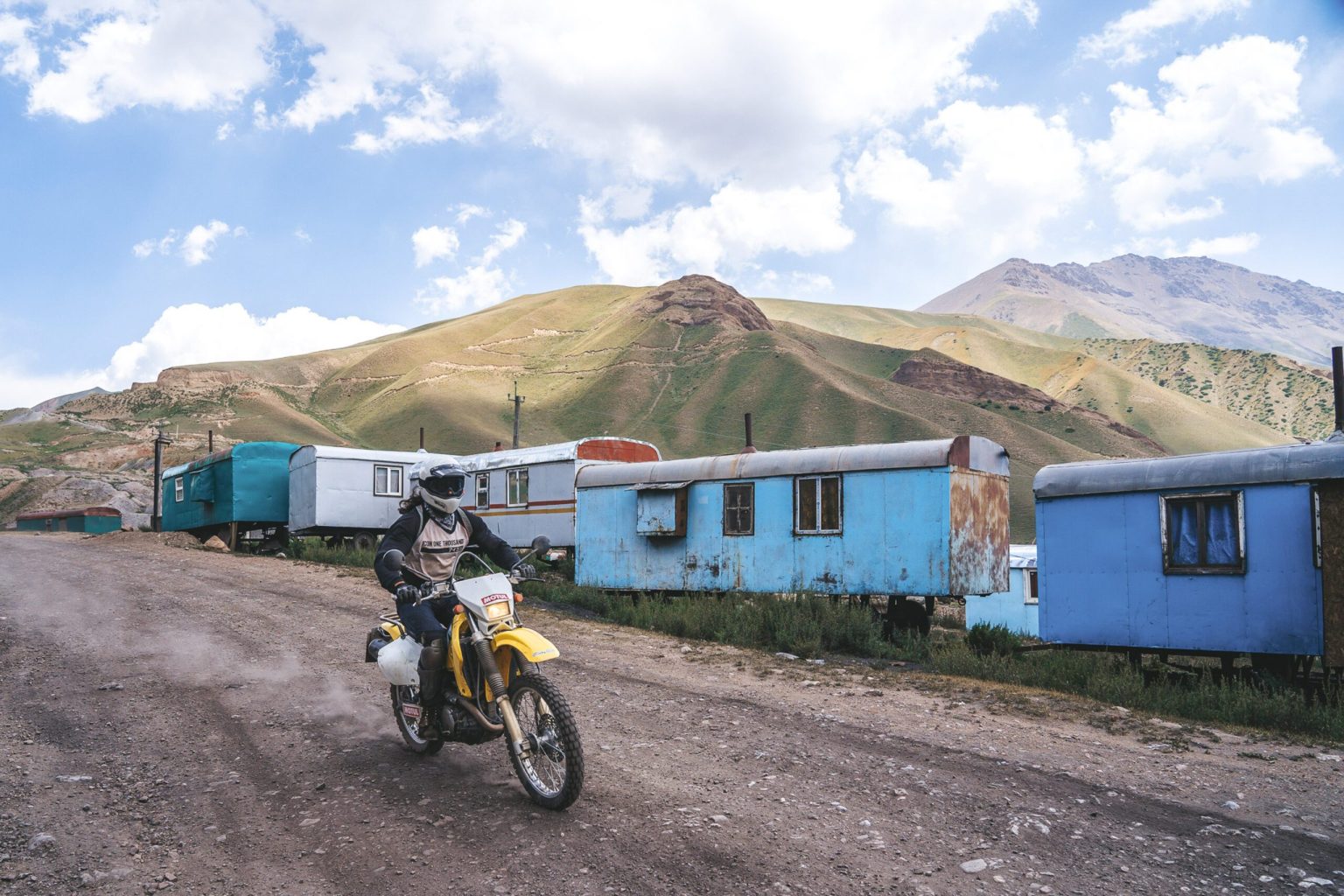 Rider passing a blue roadside building in the Kyrgyz mountains