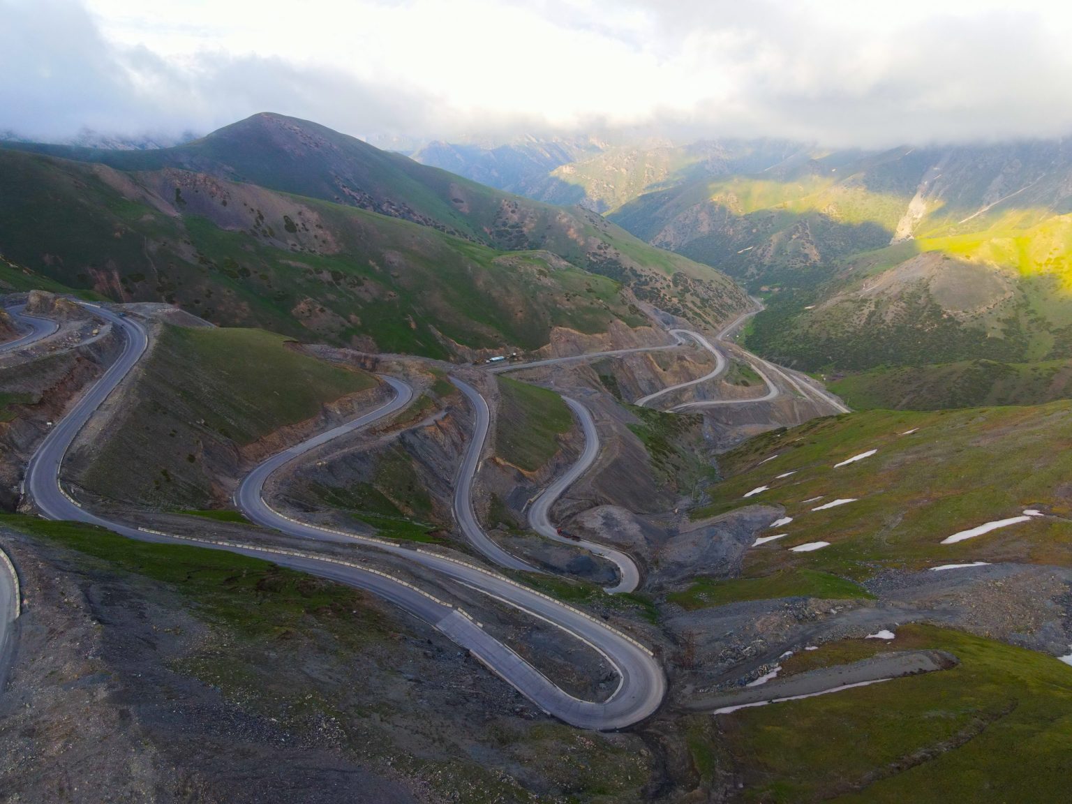 Hairpin bends of a mountain road climbing green slopes in Kyrgyzstan