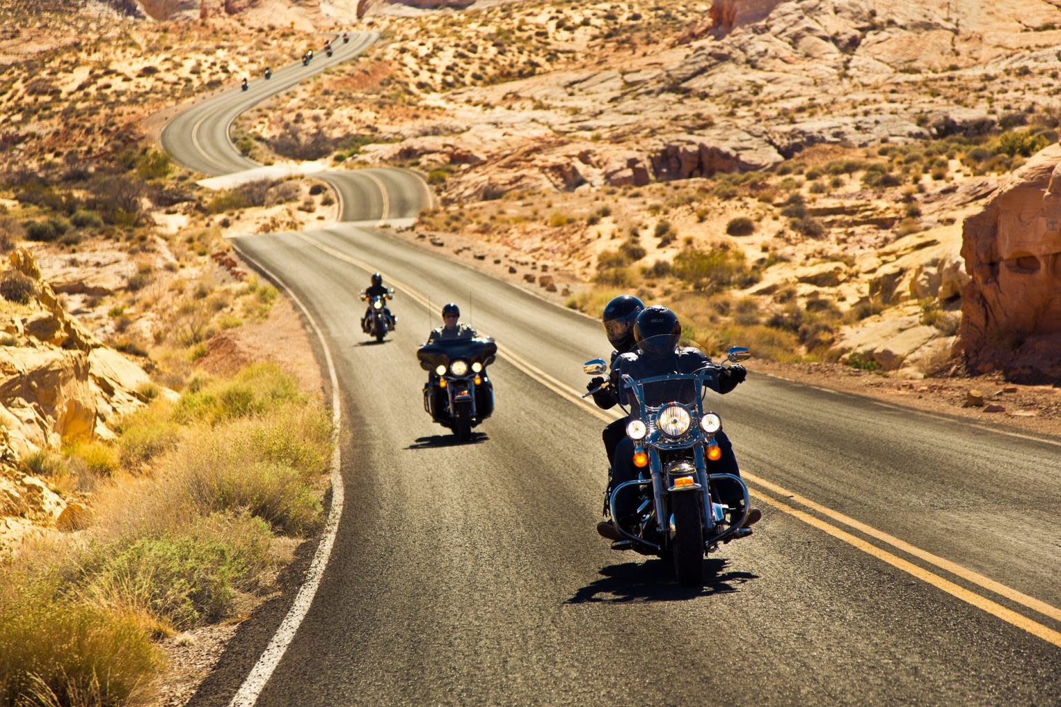 Motorcyclists riding a winding road through red desert rock in the American Southwest