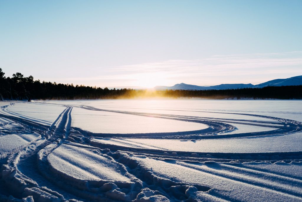 Snowmobile tracks on a frozen lake at sunset, Lapland