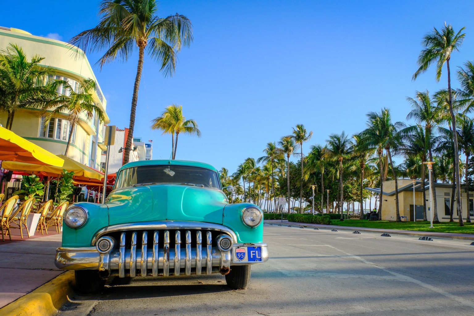 Classic turquoise car parked outside Art Deco buildings in Miami Beach