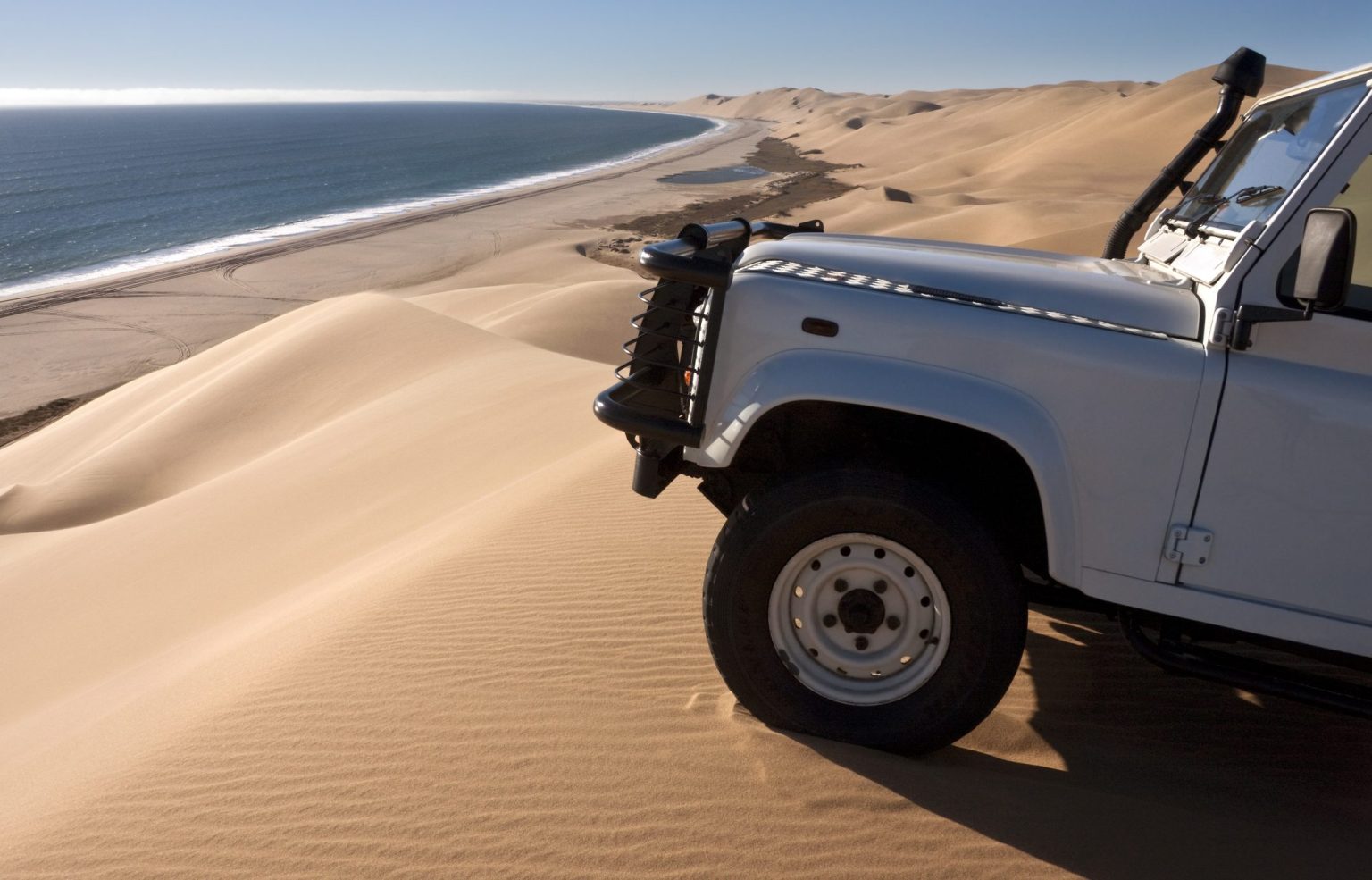 Land Rover Defender on the dunes at Sandwich Harbour above the Atlantic