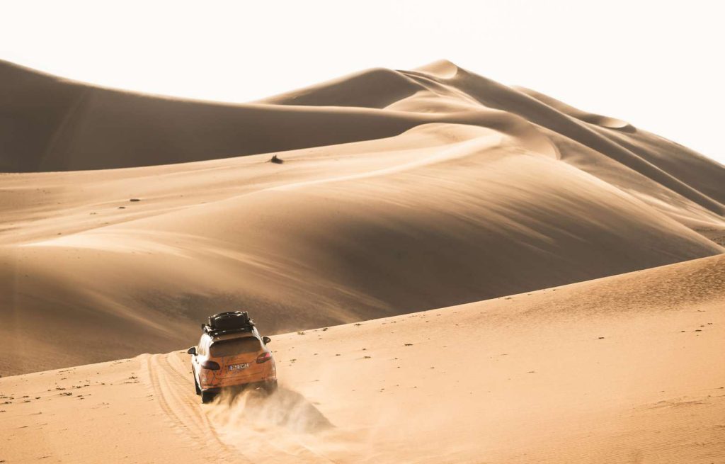 Classic car cresting the sweeping dunes of the Namib