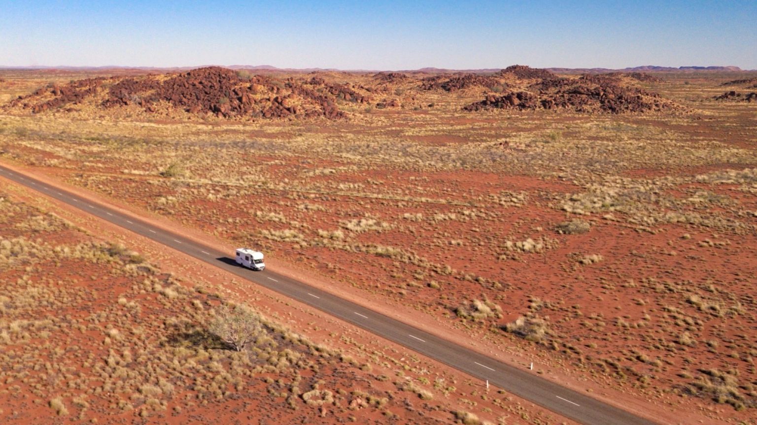 Aerial view of a road through red outback plains, between Karijini and Exmouth, Western Australia