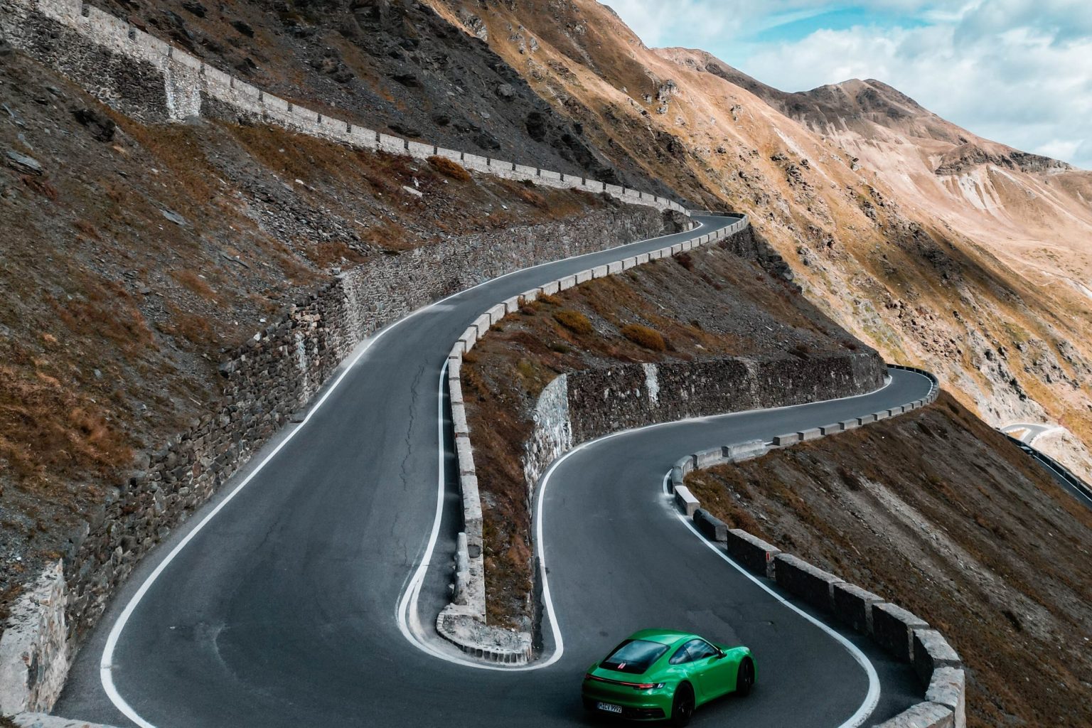 Green Porsche 911 on the hairpins of the Stelvio Pass