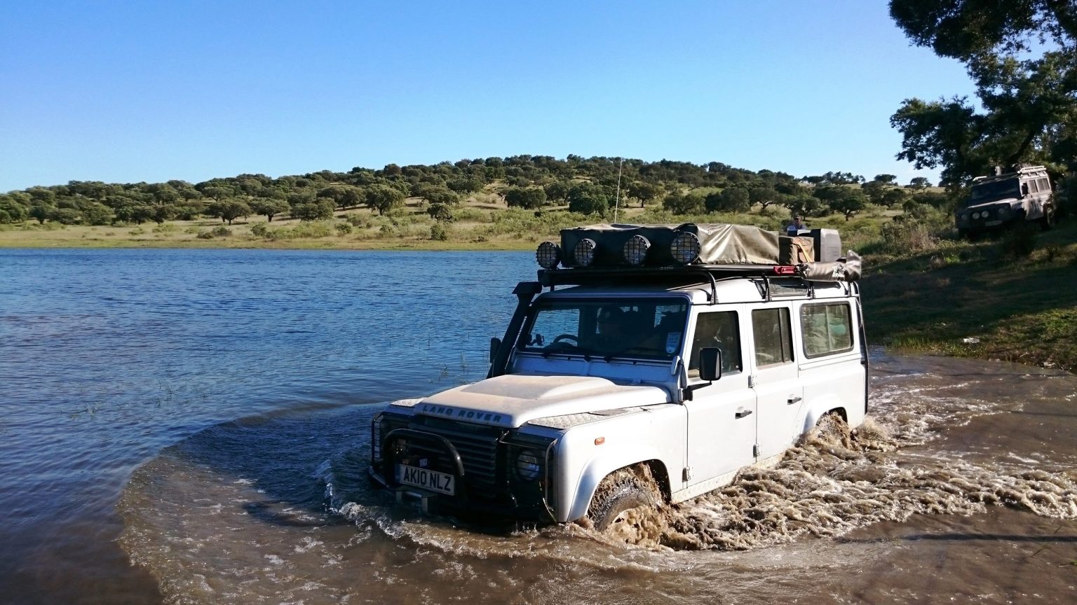 Land Rover Defender wading through a lake shallows in Portugal
