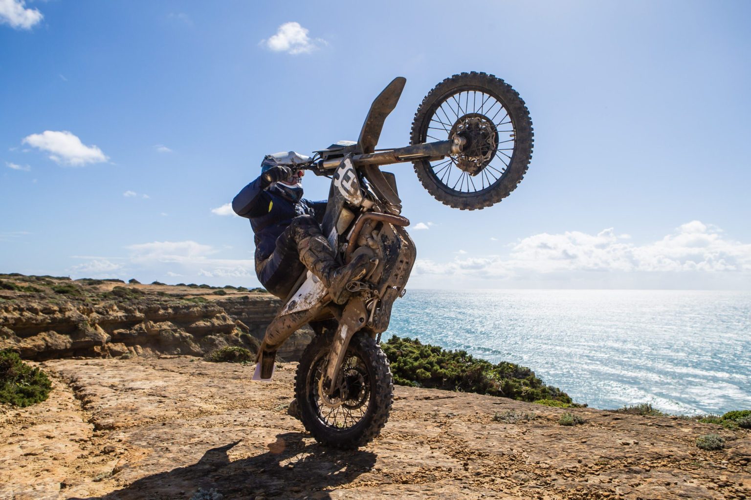 Rider pulling a wheelie on a clifftop above the Atlantic, Portugal