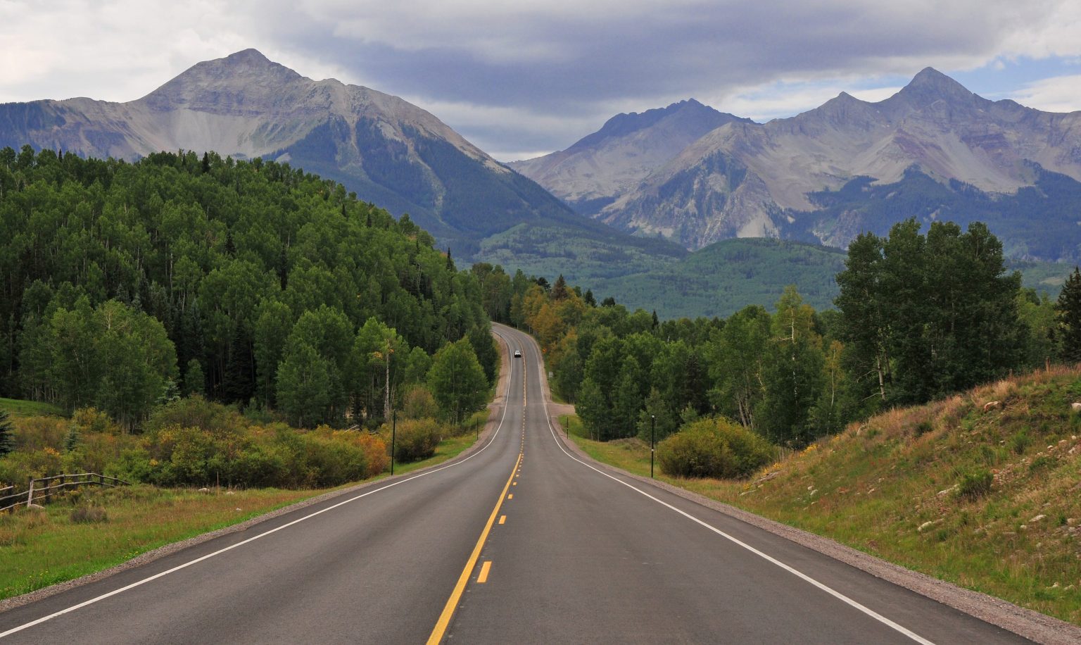 Open road heading towards rugged Rocky Mountain peaks