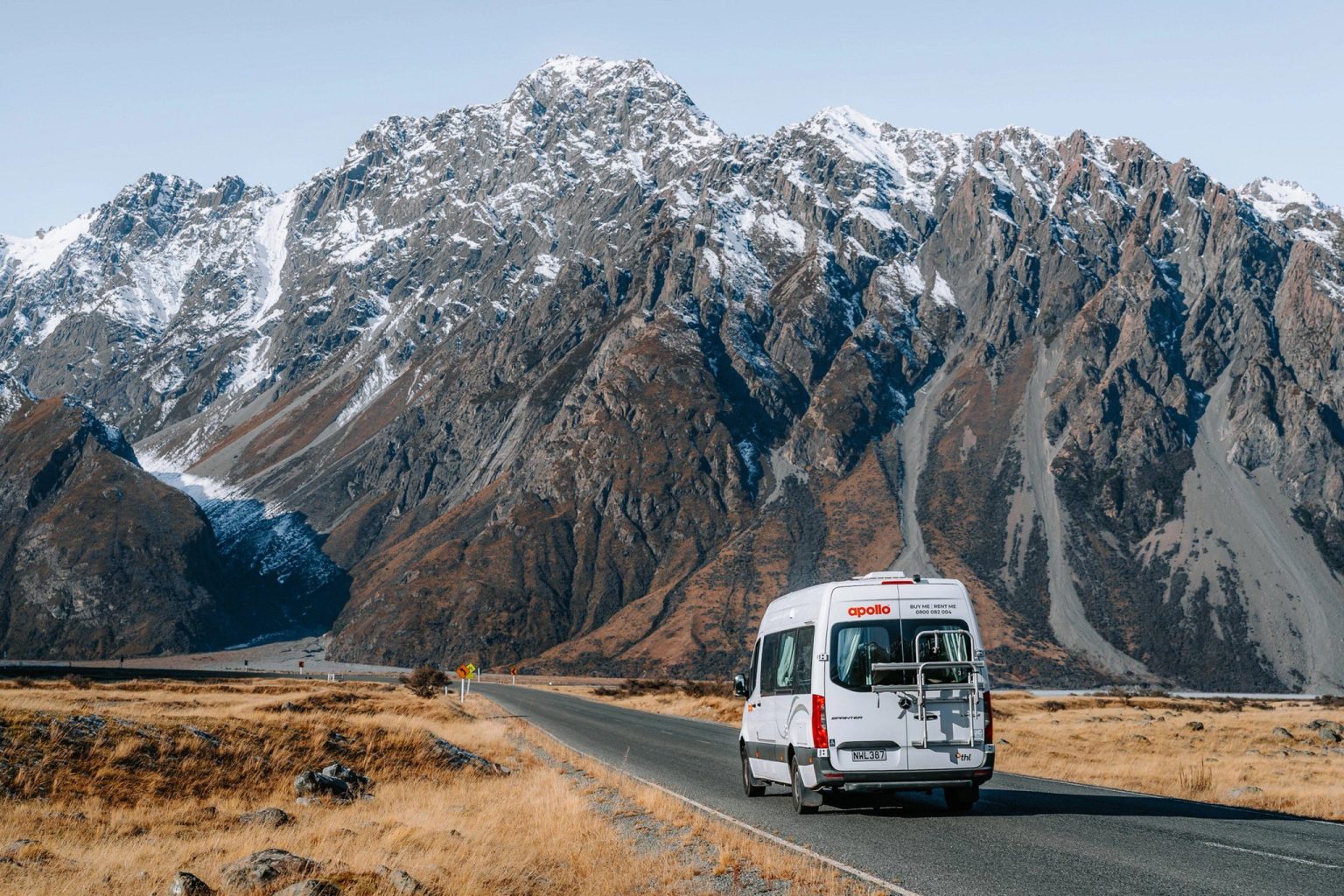 Campervan on a road below jagged snow-dusted mountains, Mount Cook, New Zealand's South Island