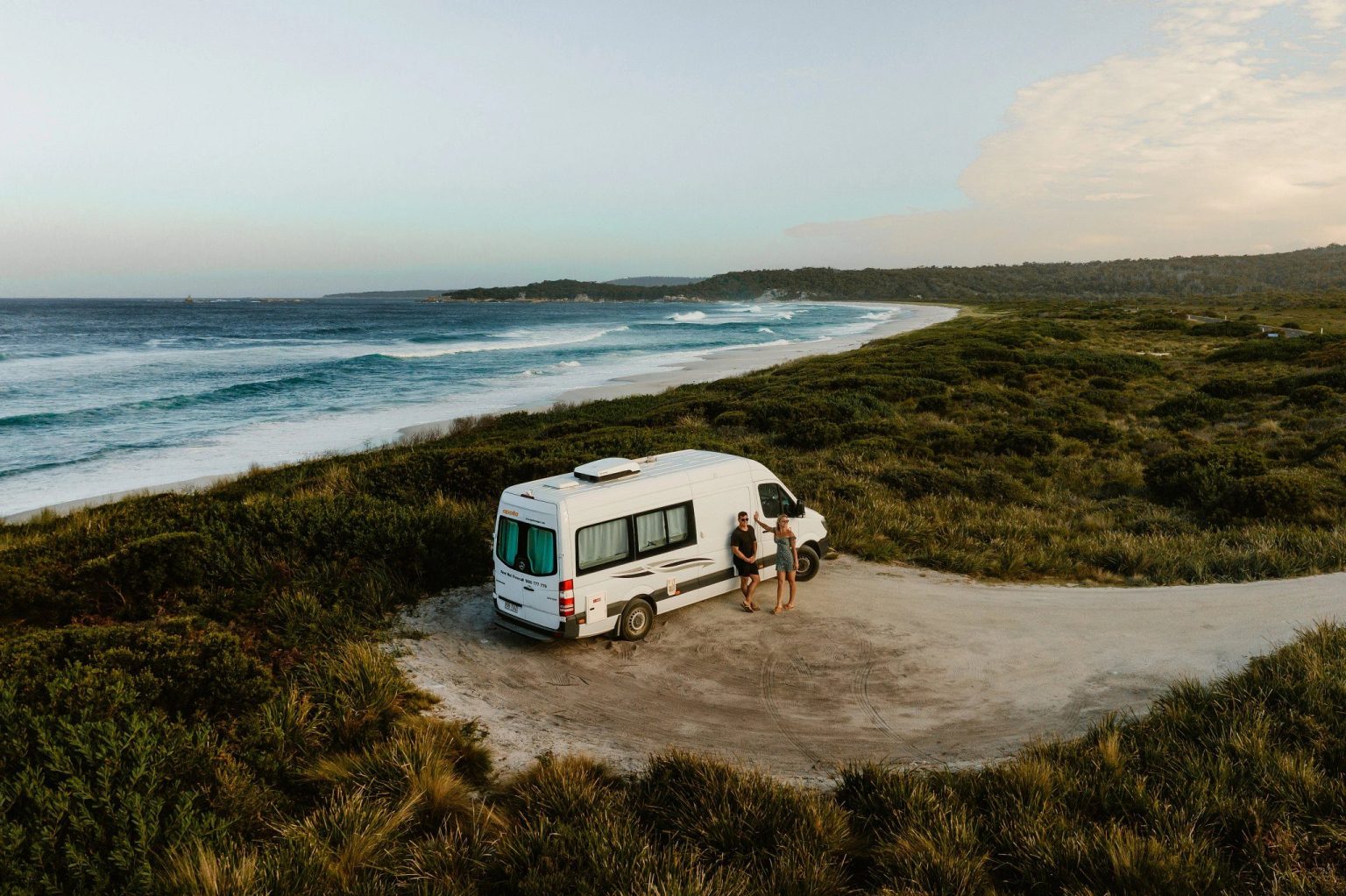 Campervan parked on a grassy clifftop above a wide beach, Hobart, Tasmania