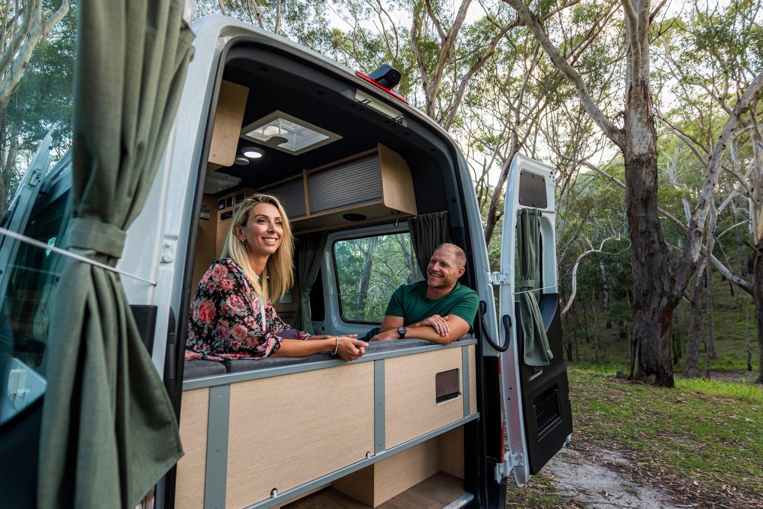 Couple chatting inside a campervan with open rear doors, Tweed Heads, New South Wales