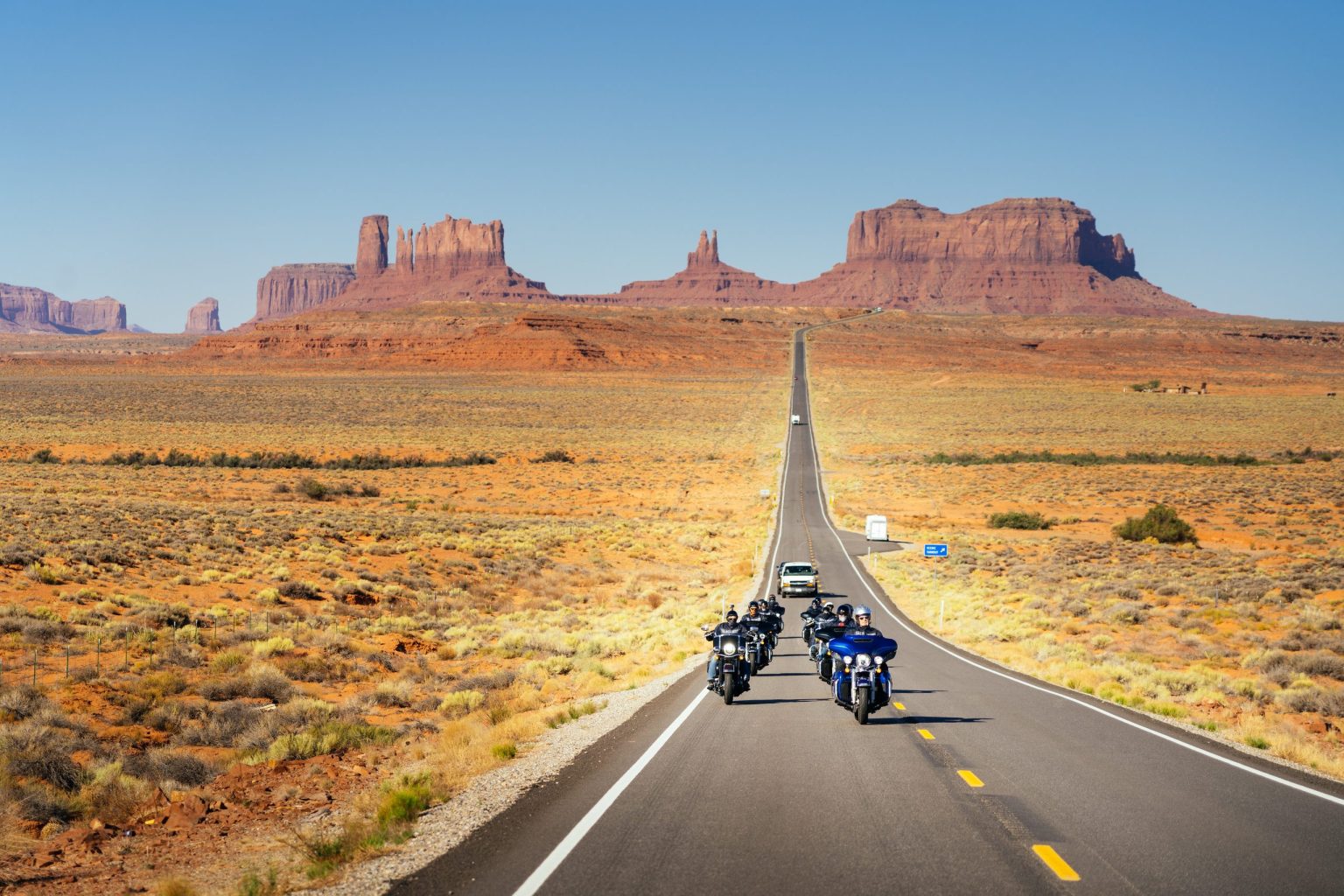 Motorcyclists on the long straight road into Monument Valley